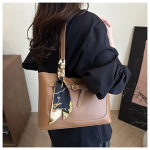 Gros plan sur un sac fourre-tout marron avec boucle métallique et foulard en soie
