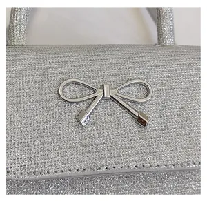 Close-up of a silver glitter evening bag featuring a minimalist metallic bow decoration