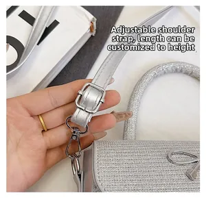 Detail of adjustable shoulder strap with silver lobster clasp on sequined handbag