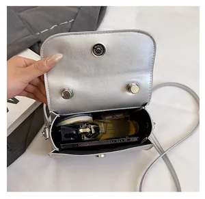 Detail view showing interior capacity of a silver metallic crossbody bag with magnetic flap