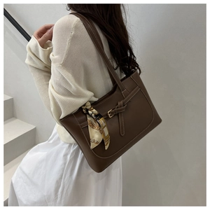 Detail of dark brown tote bag with white contrast stitching and decorative silk scarf