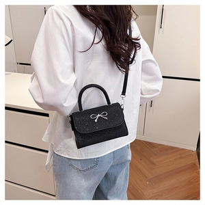 Détail du sac à main noir à paillettes avec nœud argenté et bandoulière en cuir