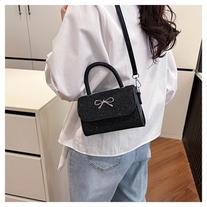 Détail du sac à bandoulière en paillettes noires avec nœud en argent et bandoulière