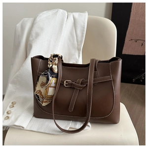 Detail of dark brown tote bag with contrast stitching and patterned silk scarf handle