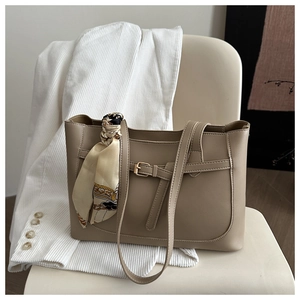 Detail of khaki tote bag with chic silk scarf on handle and decorative buckle strap