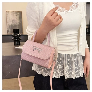 Petit sac rose pailleté avec nœud argenté porté par un mannequin dans un salon chic