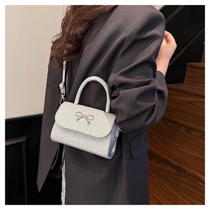 Détail du sac argenté pailleté avec nœud métallique et poignée supérieure chic