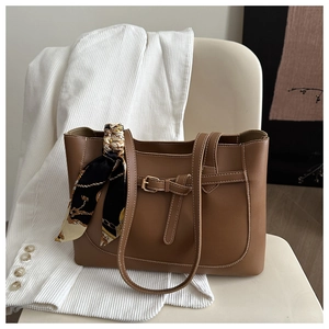 Detail of brown leather tote bag with printed silk scarf and adjustable buckle accent