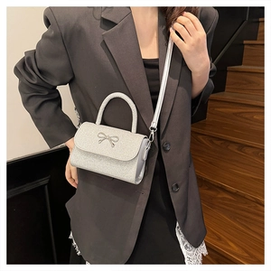 Détail du sac à bandoulière argenté brillant avec nœud métallique et bandoulière