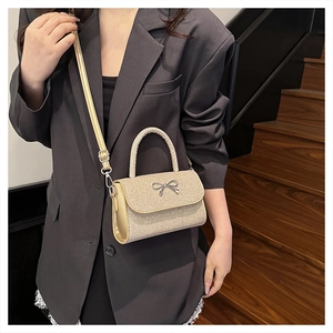 Détail du mini sac doré scintillant avec boucle nœud argentée et poignée tressée ronde