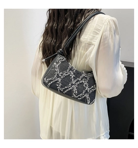 Detail of denim shoulder bag with white fringe rhombus pattern and leather strap