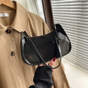 Glossy black patent leather baguette bag with a sleek minimalist shoulder strap design