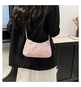 Detailed shot of pink tweed crescent bag with distressed quilted pattern on female model