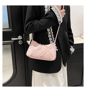 Dettaglio borsa baguette in tweed rosa con trama sfrangiata e tracolla sottile