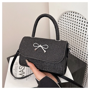 Detail of black glitter mini handbag with silver bow charm and crossbody leather strap