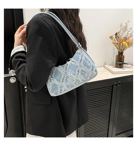 Dettaglio della borsa a tracolla in denim azzurro con cuciture trapuntate e bordi sfrangiati