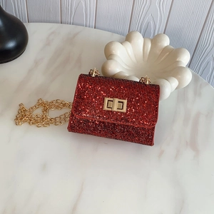 Chic red sequined mini crossbody bag with gold chain strap on marble table