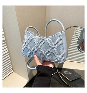 Detail of light blue denim crescent bag with white frayed fringe diamond texture