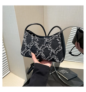 Close-up of black denim handbag featuring white tassel fringe diamond pattern detailing