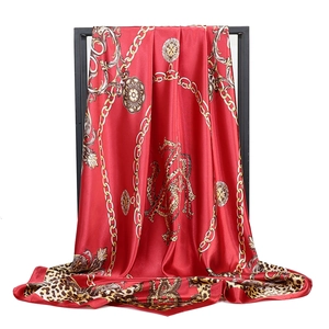 Foulard en soie rouge avec imprimé léopard et chaînes dorées sur un support noir