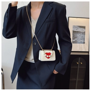 Détail du mini sac bandoulière crème avec cœur rouge, perles et chaîne dorée