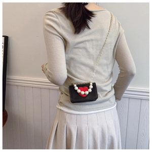Détail du mini sac bandoulière noir avec cœur rouge et bandoulière en perles