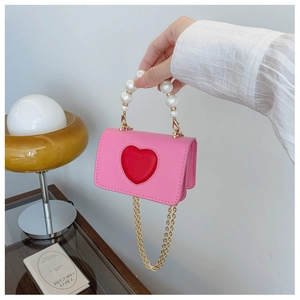 Détail du sac bandoulière cœur rose avec poignée en perles et chaîne dorée élégante