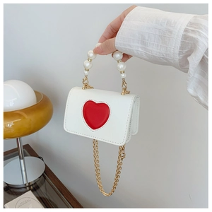 Détail du mini sac ivoire avec patch cœur rouge et poignée en perles élégantes