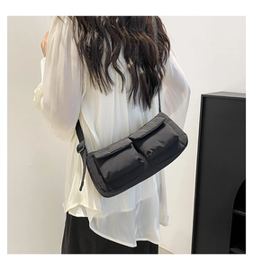 Model view of black nylon crossbody bag with dual front pockets and adjustable strap