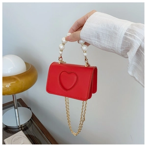 Gros plan d'un mini sac à main rouge avec relief en cœur et poignée en perles