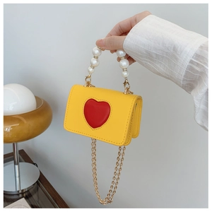 Détail du sac à bandoulière jaune avec patch cœur rouge et poignée élégante en perles