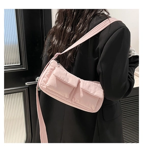 Detail of pink nylon shoulder bag with front flap pockets on a black blazer