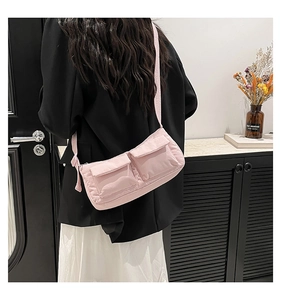 Dettaglio di una borsa a tracolla in nylon rosa con due tasche indossata dal modello