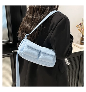 Dettaglio della borsa a tracolla in nylon impermeabile azzurro con doppie tasche anteriori