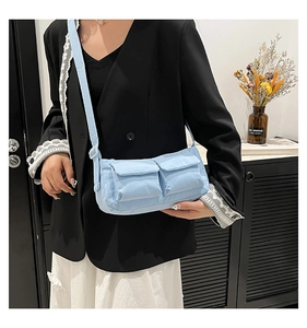 Detail of light blue nylon crossbody bag featuring dual front pockets and adjustable strap