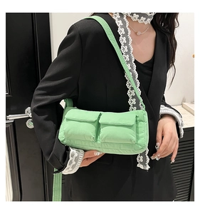 Detail view of mint green quilted shoulder bag with two utility pockets and padded texture