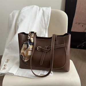 Brown leather tote bag with vintage scarf handle on a white chair for daily commute