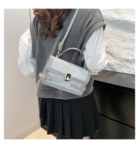 Detail of light gray textured crossbody bag with gold twist lock on a modern model