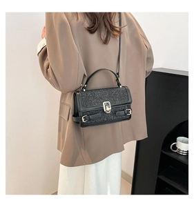 Detail of a black sequin handbag with gold metal twist lock and sparkling finish