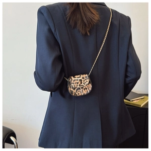 Detailed back view of a mini leopard print saddle bag with a gold chain strap on a model
