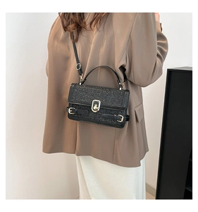Detail of black glitter crossbody bag with gold twist lock on brown blazer outfit