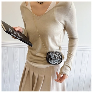 Detailed view of gray leopard print saddle bag with heart charm and gold chain strap