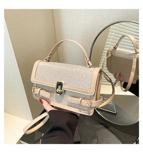 Detail of elegant beige crossbody bag showing glitter texture and gold metal buckle
