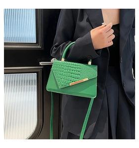 Dettaglio borsa a mano verde con trama a coccodrillo e decorazioni dorate