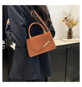 Dettaglio della borsa marrone con motivo a coccodrillo indossata da una modella elegante