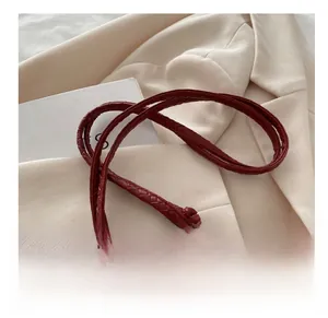 Detail of red woven shoulder bag with knotted strap and silver zipper closure