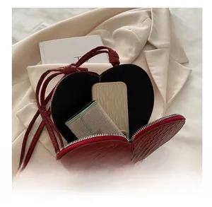 Internal capacity of the heart-shaped woven crossbody bag showing phone and wallet