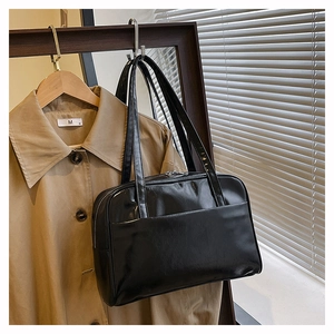 Detail of black glossy PU leather pillow bag with silver zipper and shoulder straps