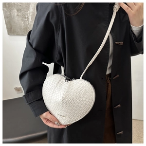 Detail of white heart-shaped crossbody bag with crocodile texture and fashion logo