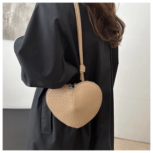 Detail of a brown heart-shaped bag with faux crocodile pattern and silver dual zippers